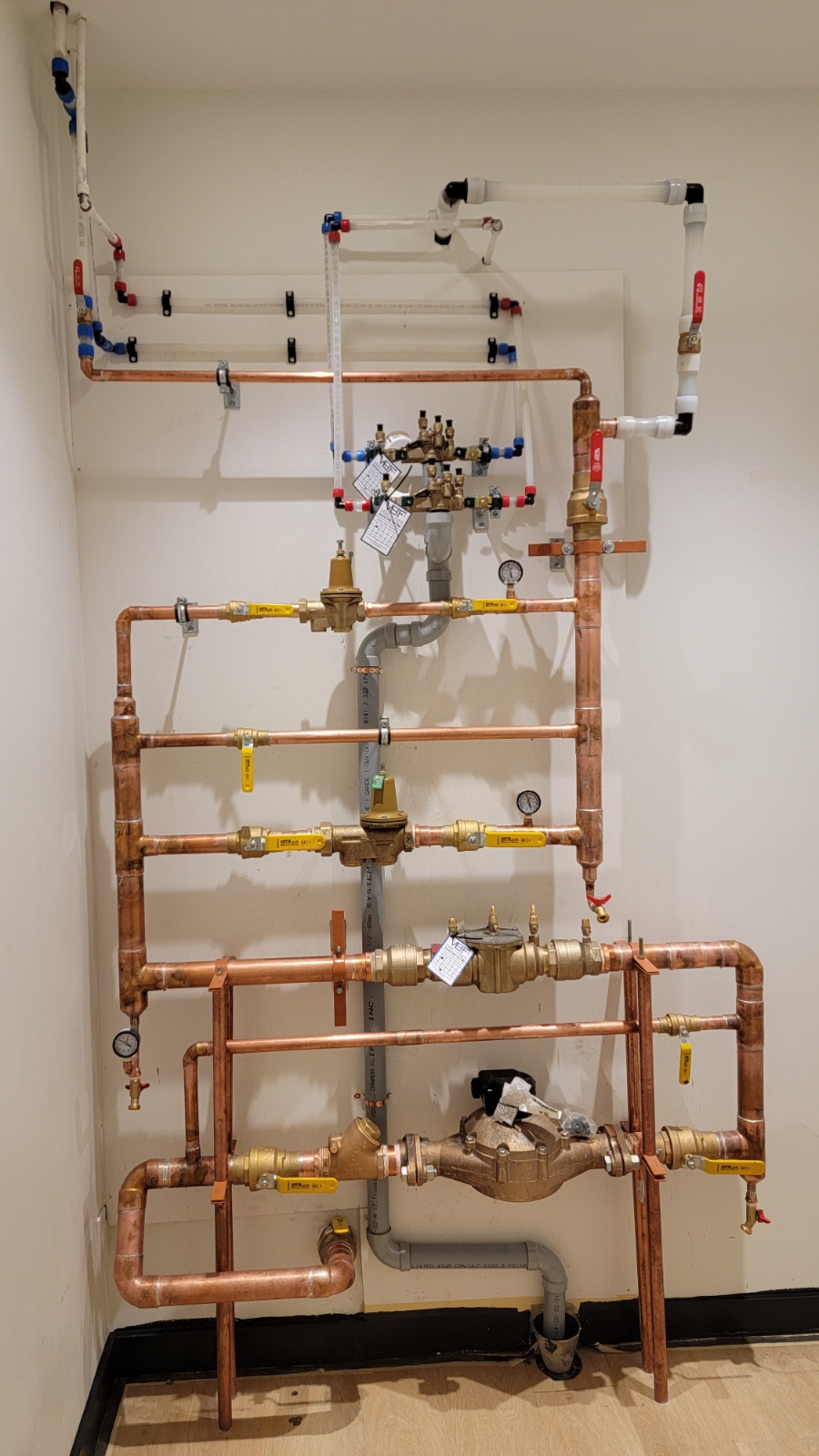 Mechanical Room — Commercial — Copper distribution piping, pressure-reducing valves, and backflow preventer in a commercial mechanical room.