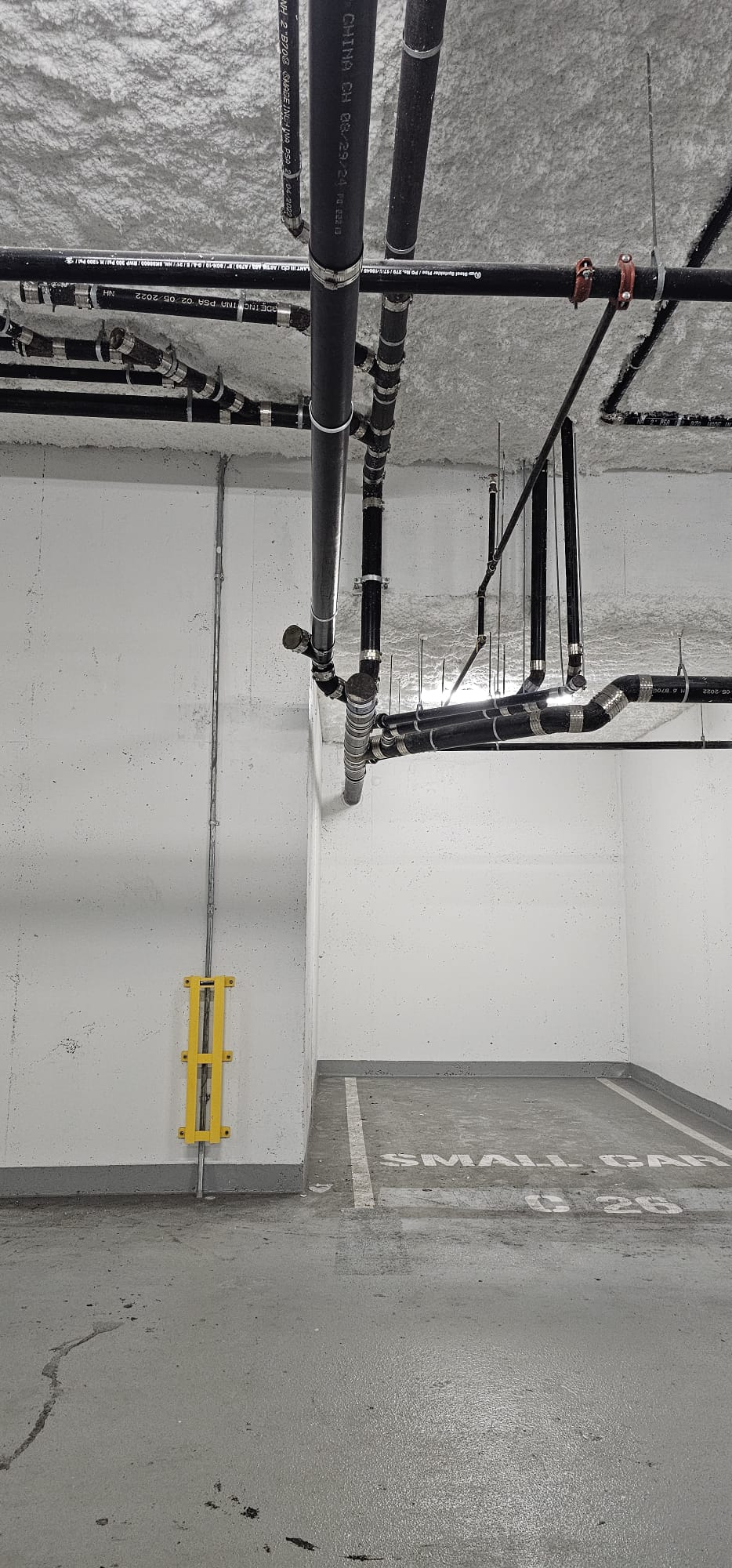 Commercial Drainage — New Build — Overhead commercial drainage and sprinkler piping run through a parkade in a new build.