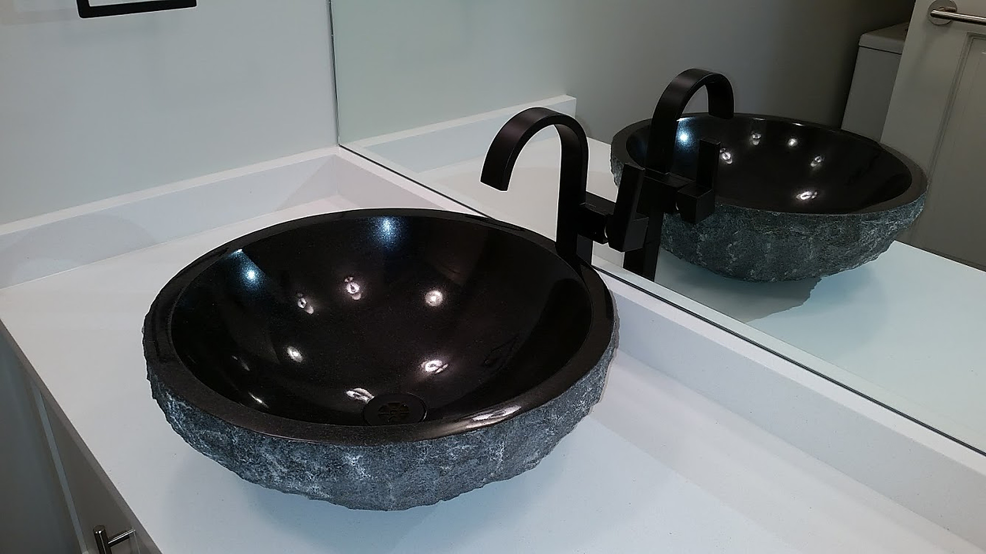 Bathroom Lavatory — Residential — Stone vessel basin with wall-mount faucet on a residential vanity.