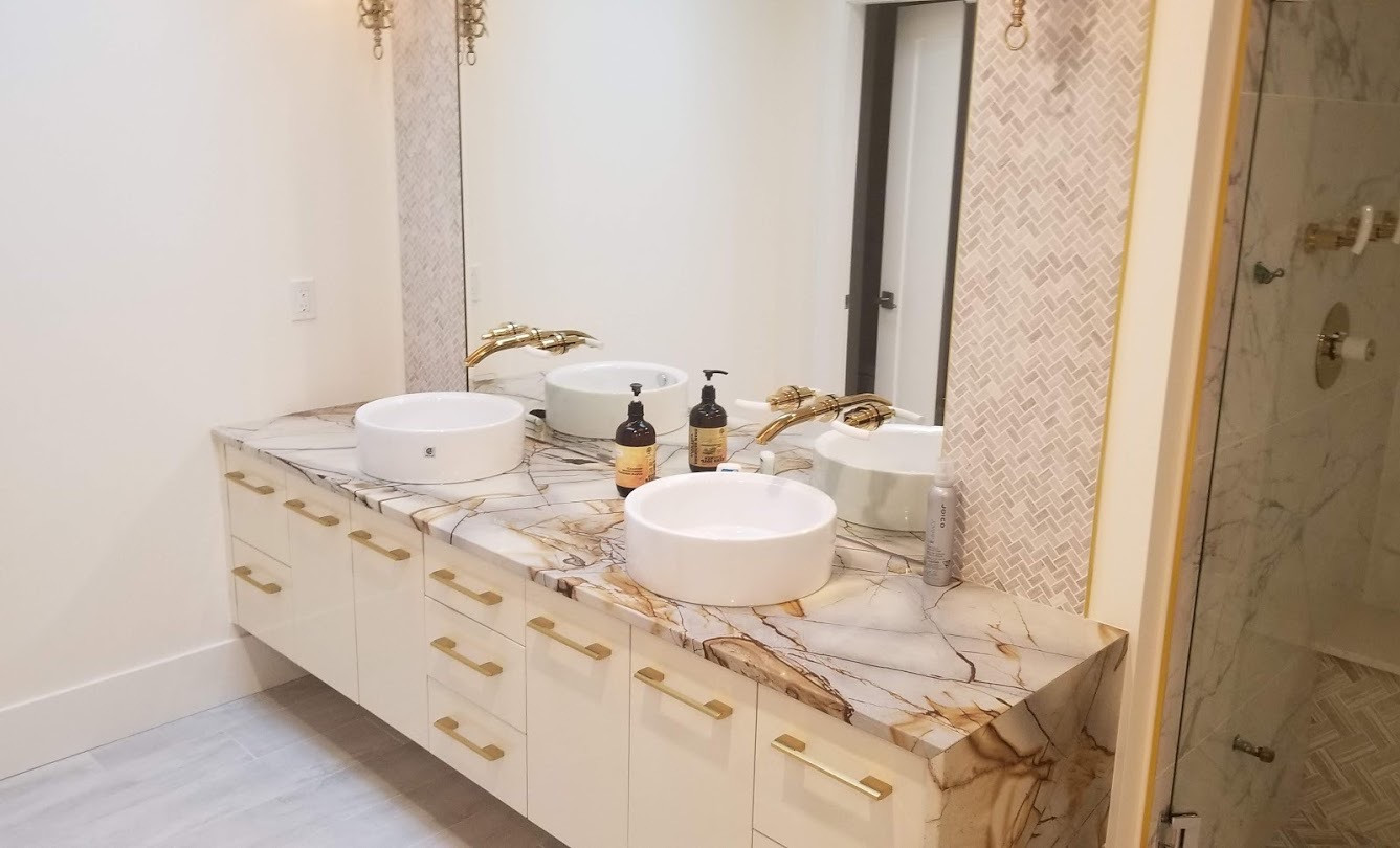 Marble Double Vanity — Vancouver Home — Gold-finished wall faucets and vessel basins on a marble double vanity in a Vancouver bathroom renovation.